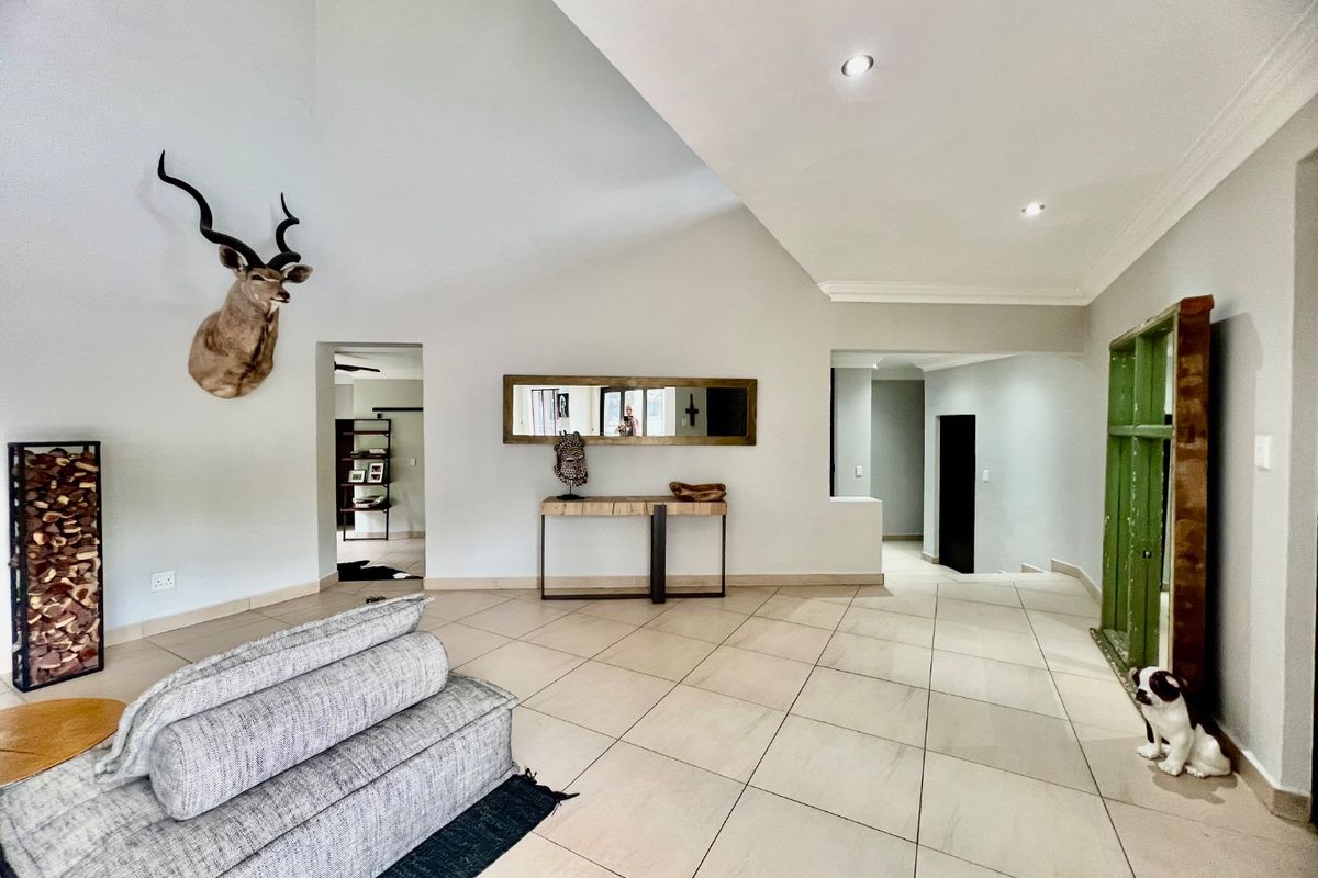Spacious living area featuring high vaulted ceilings, recessed downlighting, and neutral tiled flooring, providing an open and airy atmosphere.