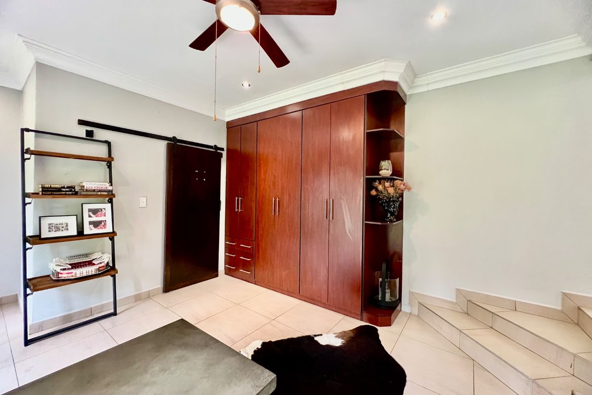 A bedroom featuring extensive built-in wooden cabinetry, a ceiling fan, tiled flooring, and a sliding barn door, providing ample storage and functional design.