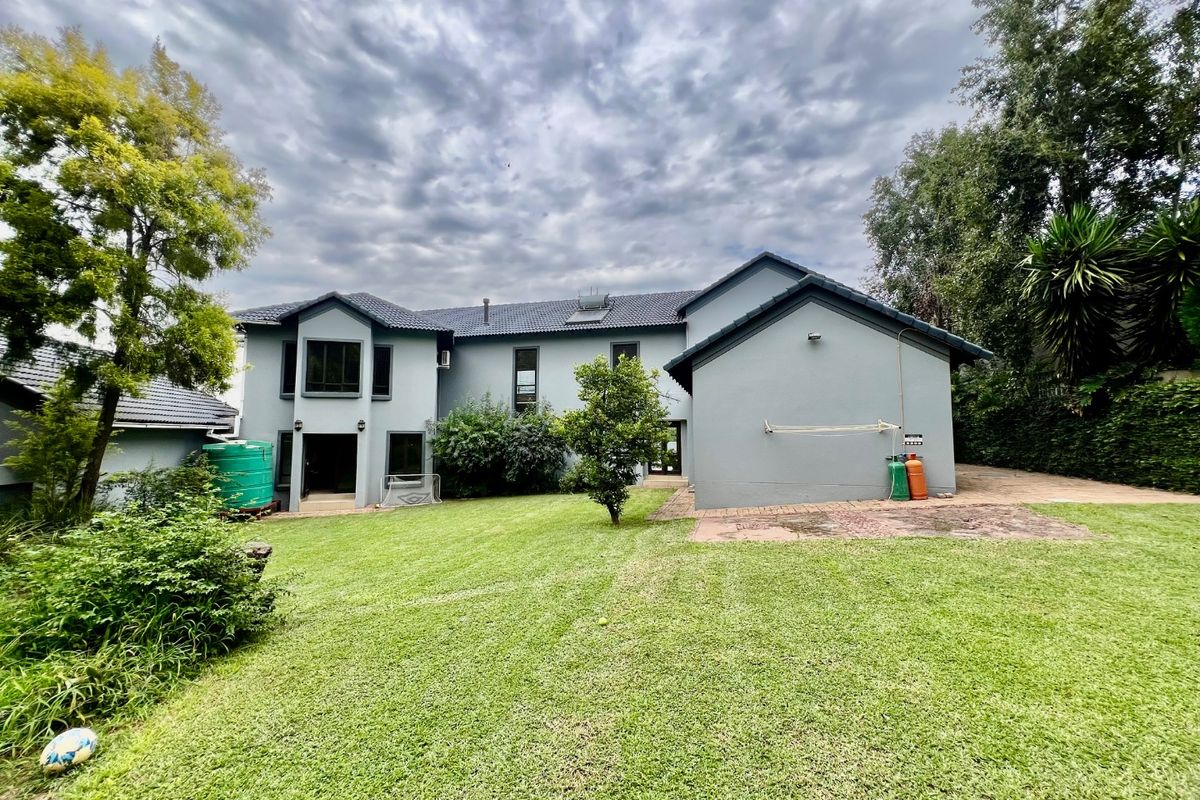 Rear view of the house featuring a spacious lawn, paved patio area, and integrated water storage tank.