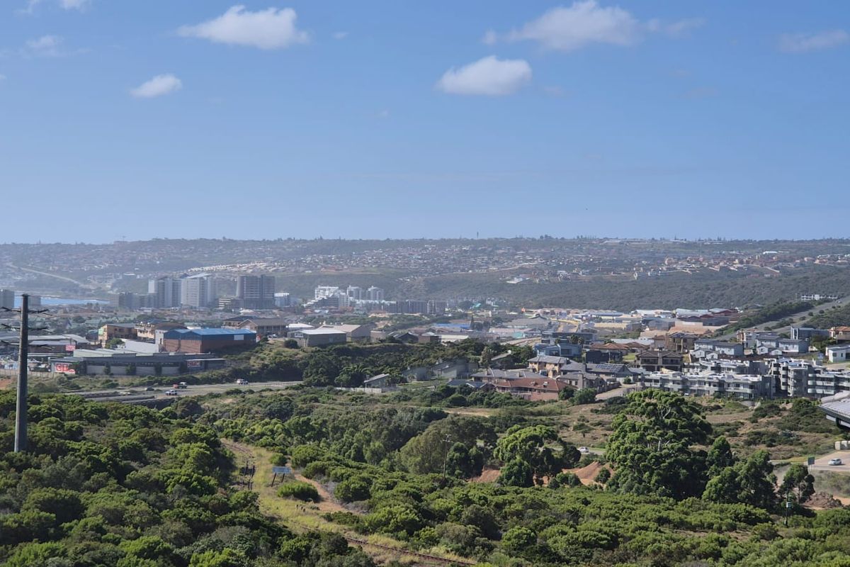 An elevated panoramic view overlooking the surrounding landscape, coastal town, and urban infrastructure.