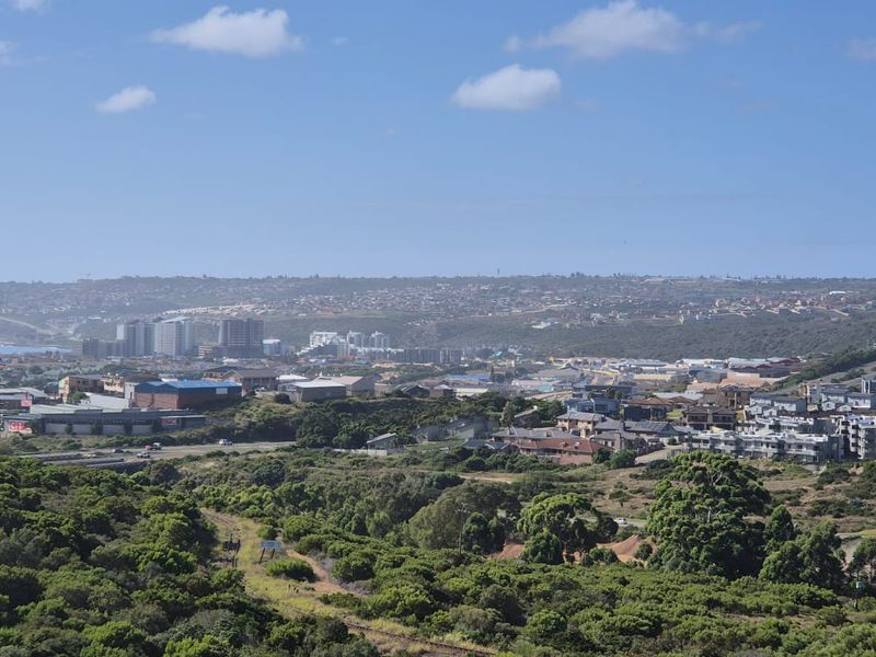 An elevated panoramic view overlooking the surrounding landscape, coastal town, and urban infrastructure.