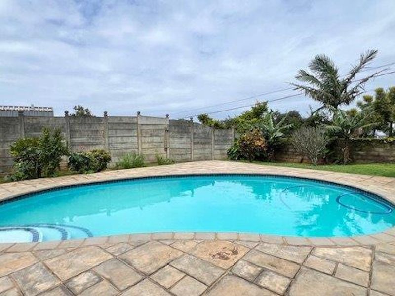 A private swimming pool area featuring a paved surround and a secure precast concrete boundary wall in a landscaped garden setting.