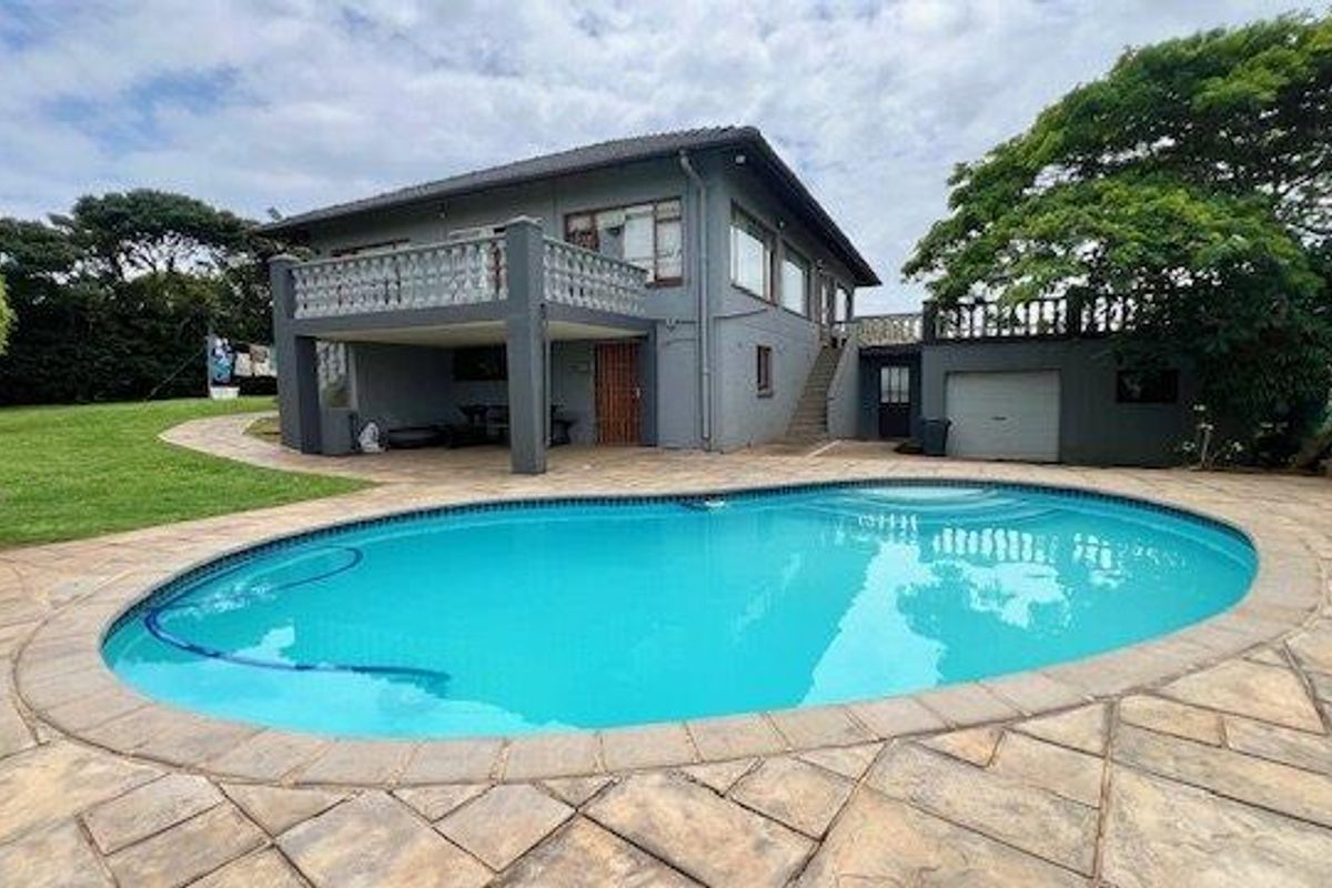 Rear exterior view featuring a swimming pool, paved patio area, elevated balcony, and external staircase access to the upper level.