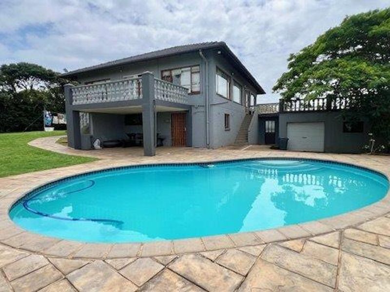 Rear exterior view featuring a swimming pool, paved patio area, elevated balcony, and external staircase access to the upper level.