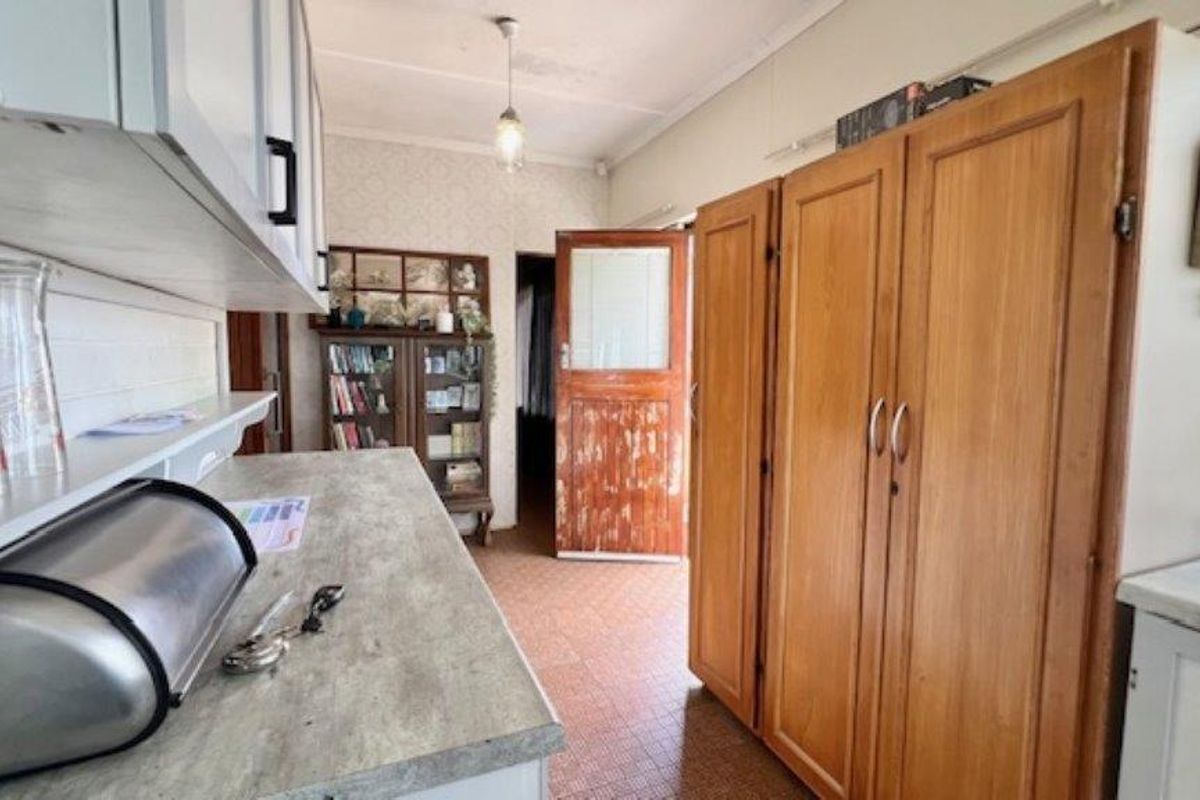 A dated kitchen area featuring built-in wooden cabinetry, laminate countertops, and original flooring, offering potential for a modern renovation.