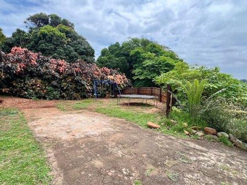 Rear garden area featuring a concrete paved section, established trees, and timber boundary fencing, offering potential for landscaping and outdoor improvement.