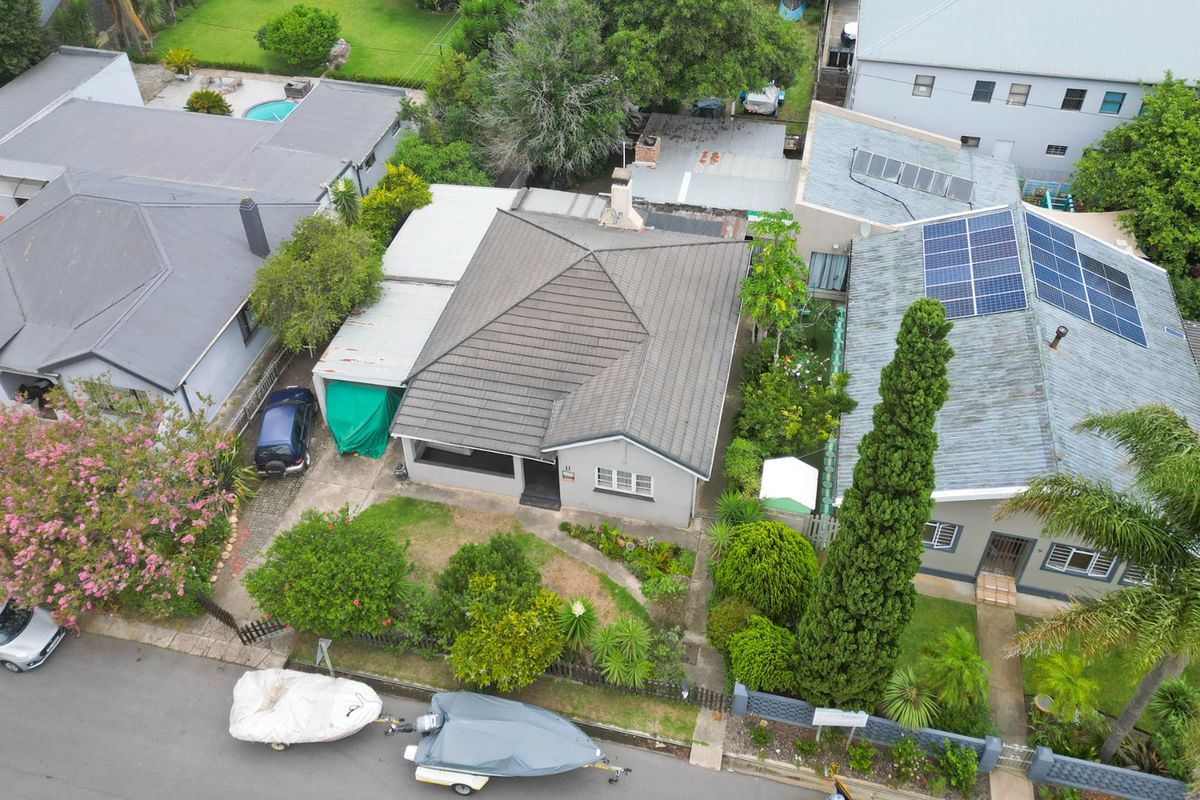 Aerial view of a residential property featuring a tiled roof, established garden, and paved driveway access from the street.