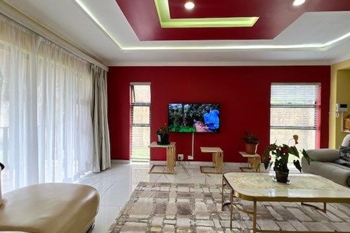 Spacious living room featuring a modern recessed ceiling with integrated LED lighting, large windows with blinds, and polished tiled flooring.