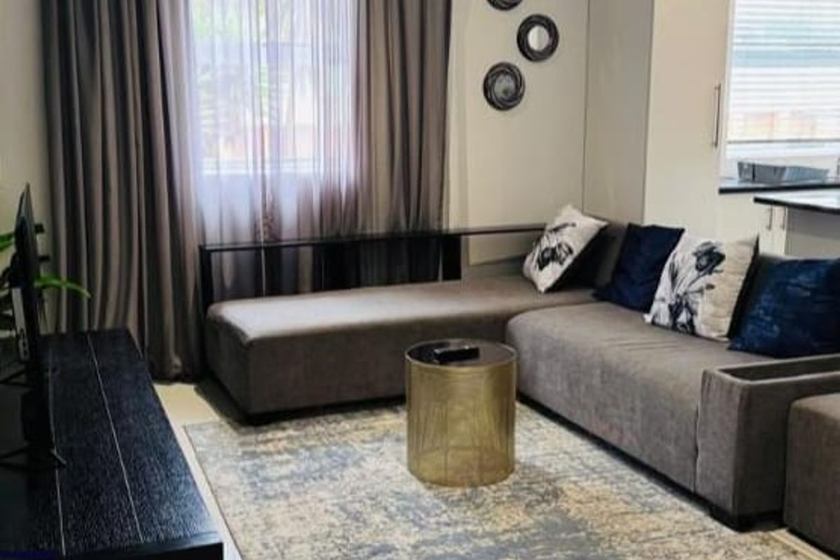 A well-maintained living room featuring neutral tiled flooring, recessed ceiling lighting, and integrated cabinetry, creating a clean and functional living space.