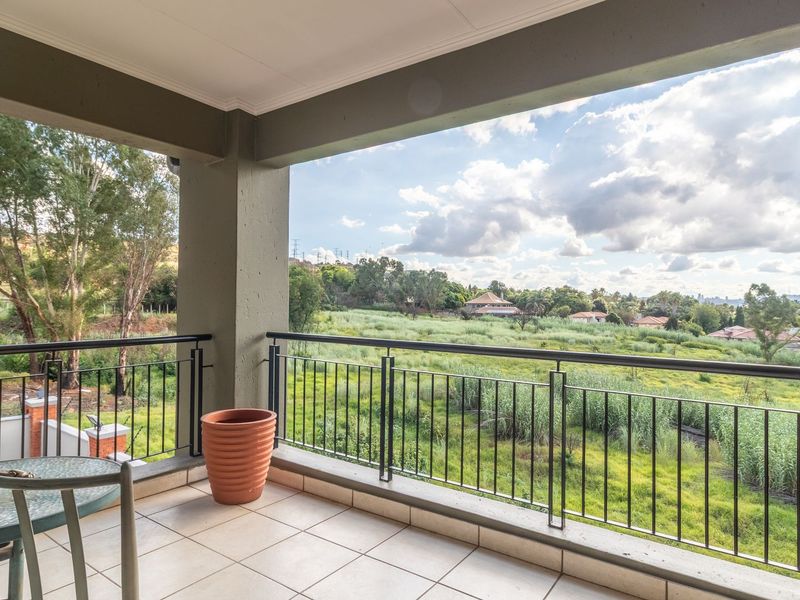 A covered balcony featuring tiled flooring, a metal balustrade, and expansive views over the surrounding landscape.