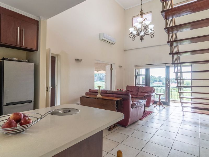 Spacious open-plan living area featuring a modern kitchen, high ceilings, an elegant open-tread staircase, and direct access to a balcony with scenic views.