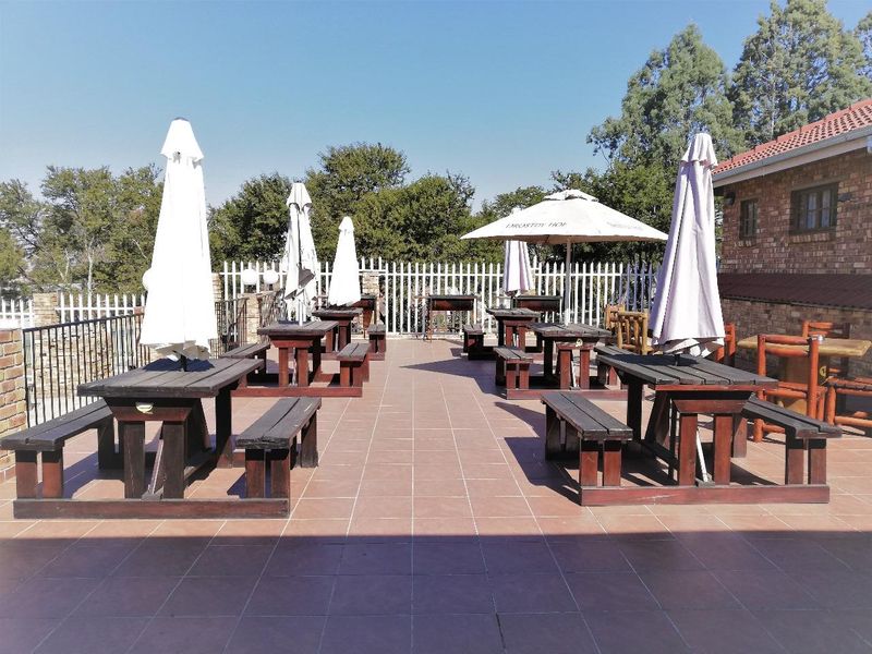 An outdoor patio area featuring tiled flooring, brick wall construction, and metal security fencing, suitable for outdoor dining and entertainment.