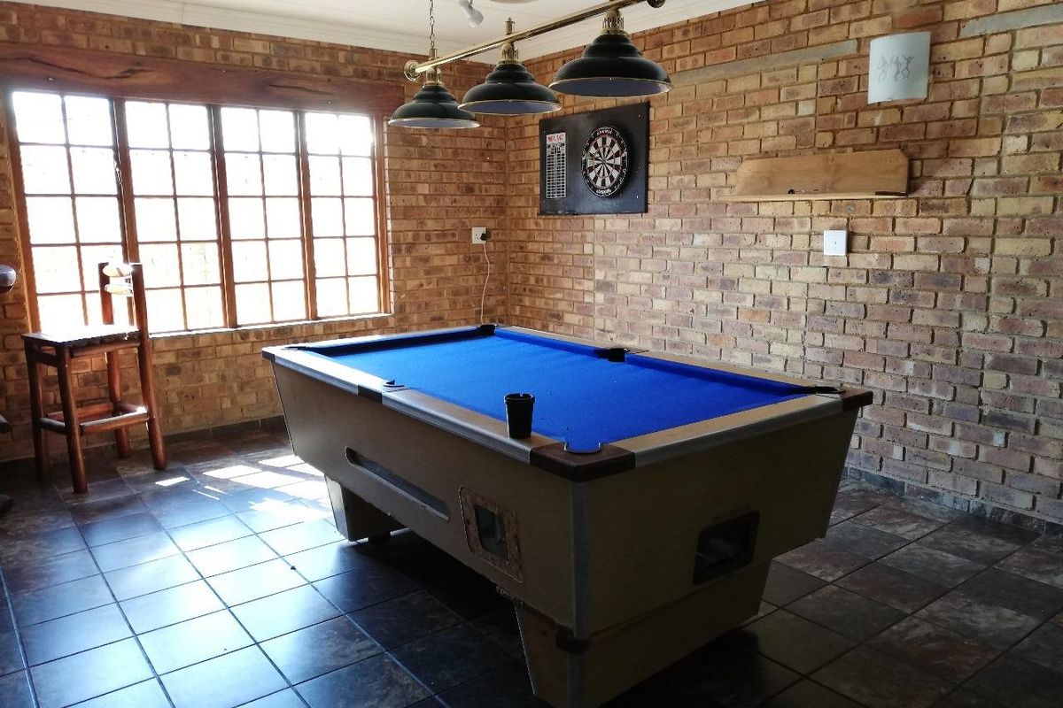 A rustic living area featuring exposed brick walls, tiled flooring, and large multi-pane windows, currently set up as a recreational space.
