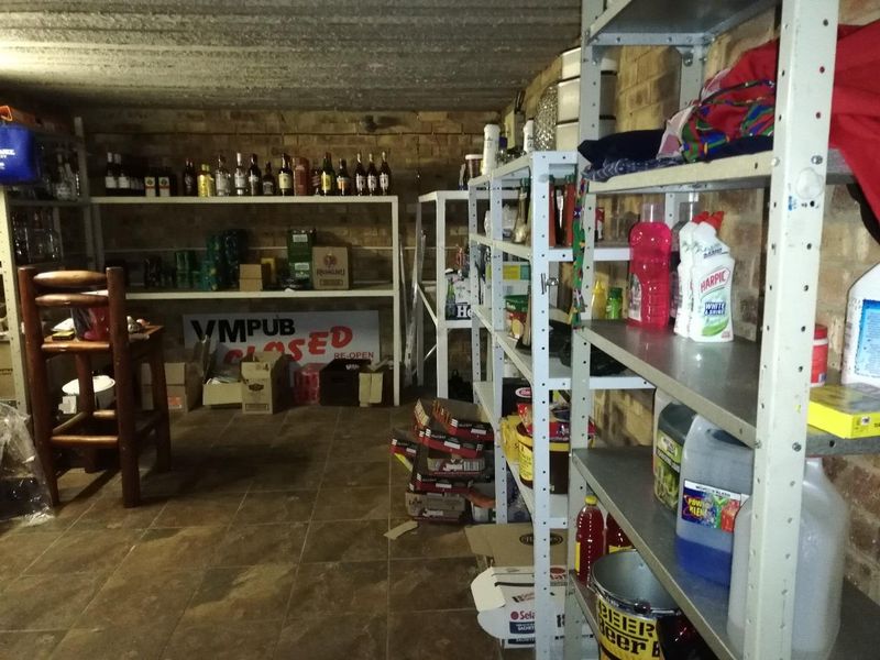 A utility storage space featuring exposed brick walls, concrete ceiling, and tiled flooring, currently utilized for general storage.