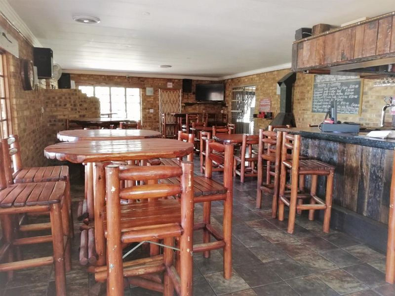 A rustic-style bar area featuring exposed brick walls, tiled flooring, a built-in bar counter, and a fireplace.