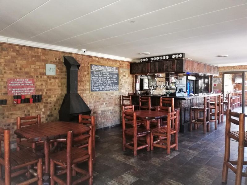 A rustic-style bar area featuring an exposed brick wall, a built-in bar counter, a metal fireplace, and tiled flooring.