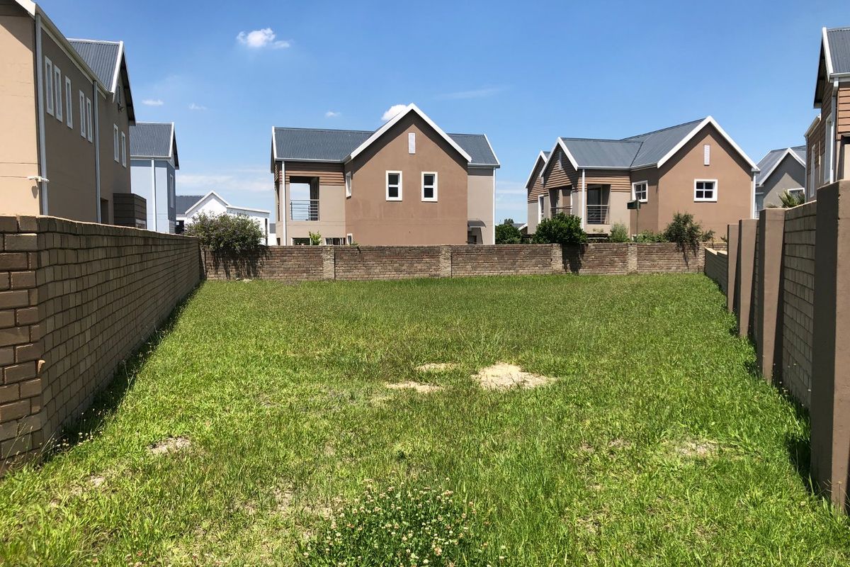 A vacant residential plot enclosed by brick boundary walls, situated within a developed estate setting.