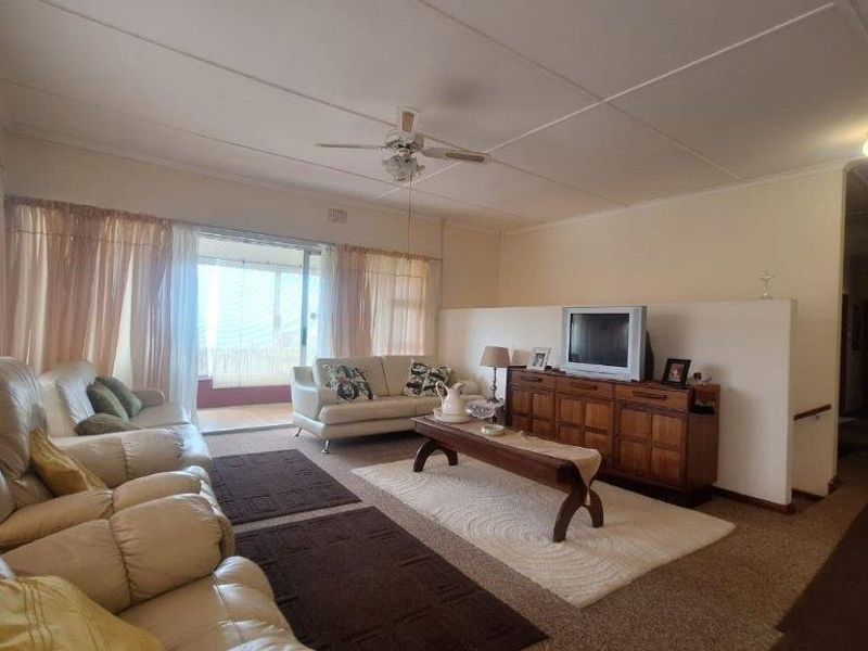 Spacious living room featuring a ceiling fan, neutral wall finishes, and a sliding glass door providing access to the outdoor area.
