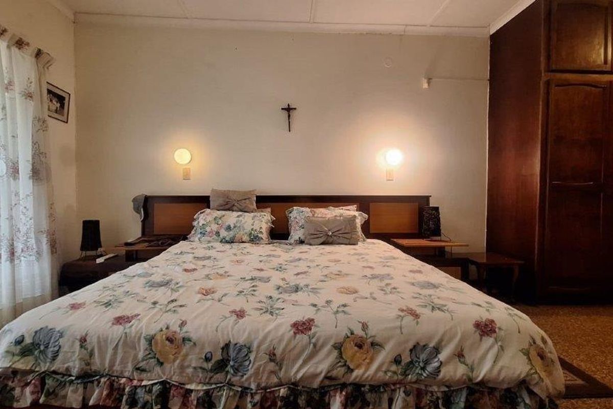 A bedroom featuring a built-in wooden wardrobe and wall-mounted lighting fixtures.