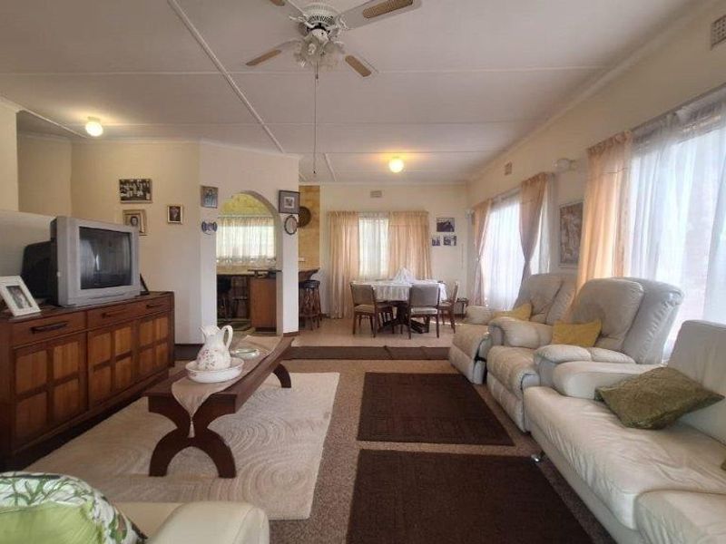 Spacious open-plan living and dining area featuring a ceiling fan, arched transition to the kitchen, and large windows allowing for natural light.