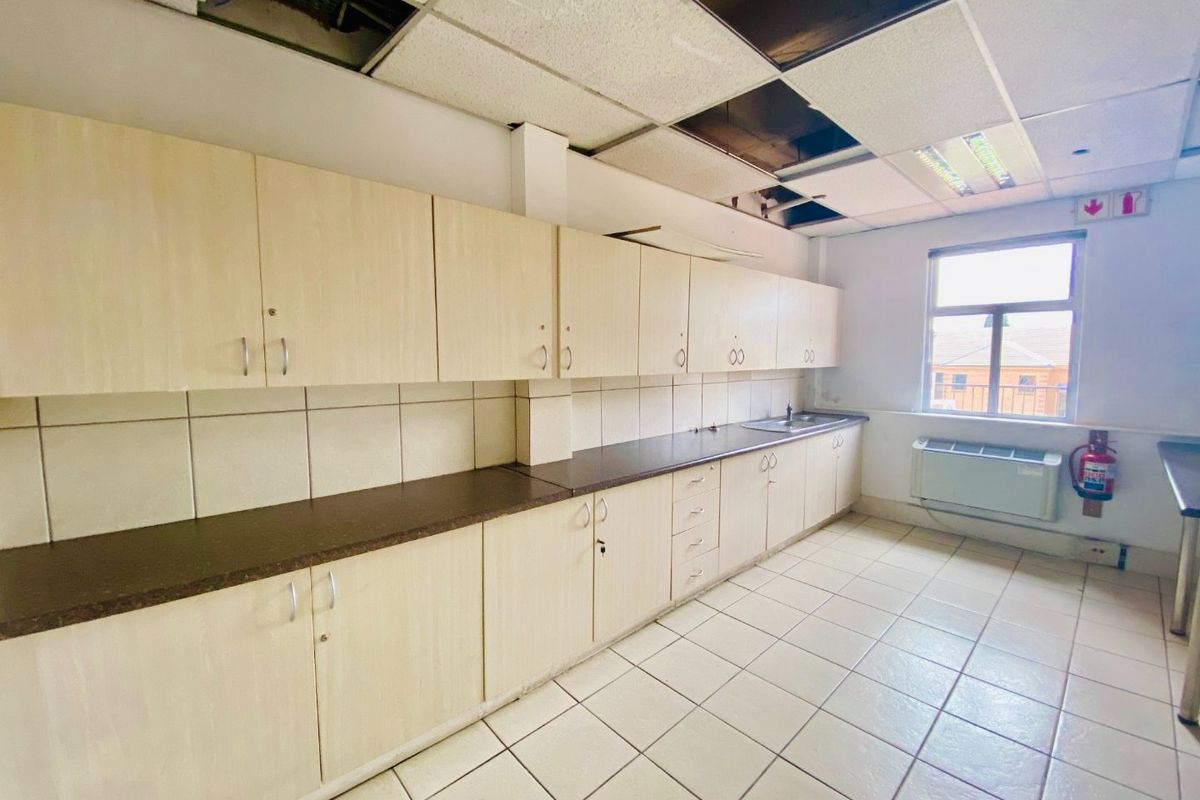 A commercial kitchen space featuring extensive cabinetry, tiled surfaces, and a sink, currently requiring ceiling repairs and general maintenance.