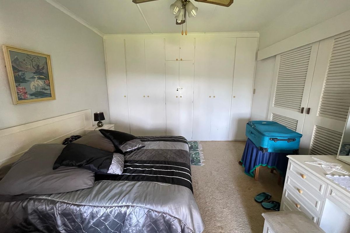 A bedroom featuring built-in cupboards, a ceiling fan, and louvered closet doors, offering a functional space with potential for cosmetic updates.