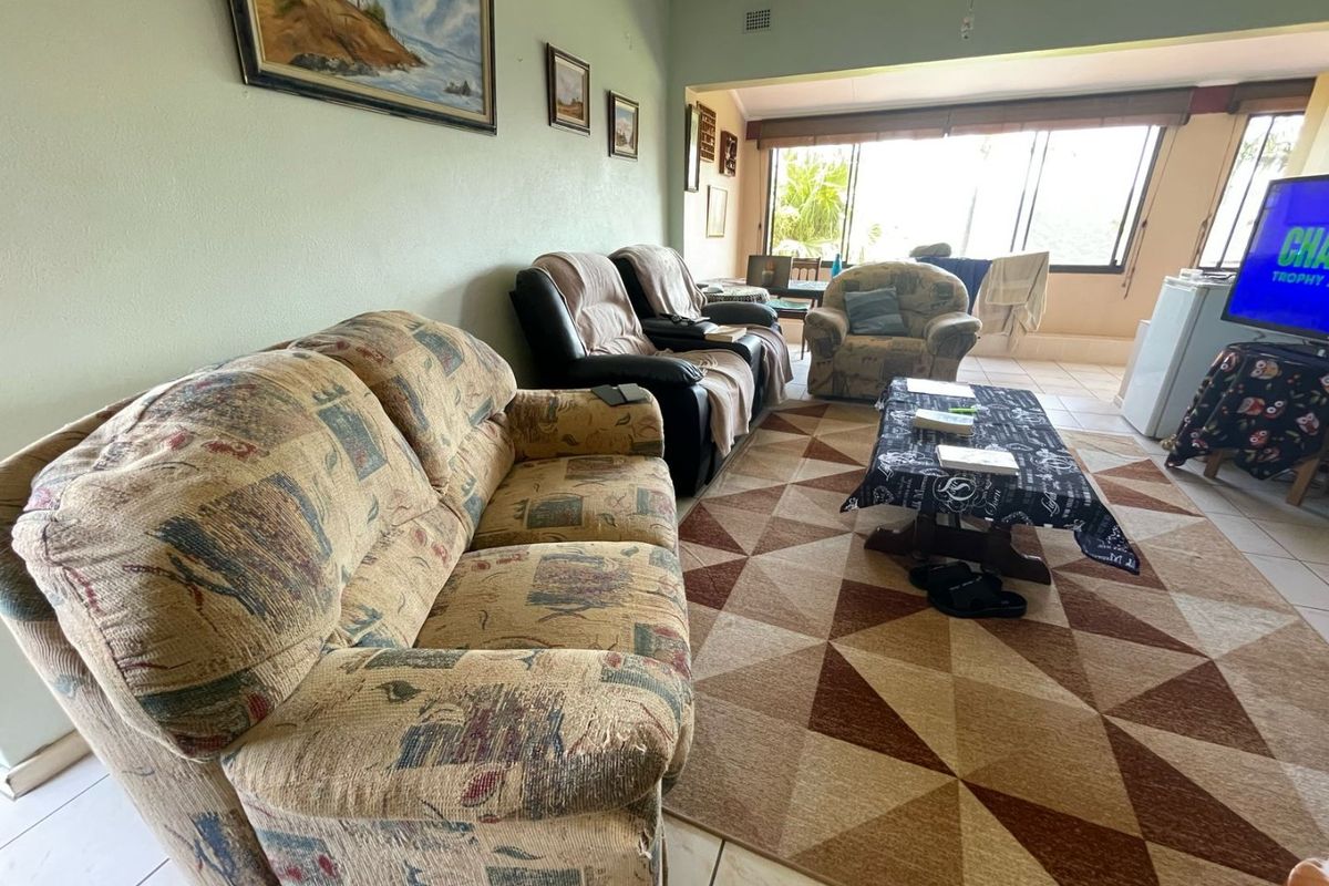 A spacious living room featuring tiled flooring and large windows that provide ample natural light, creating a comfortable and functional living space.