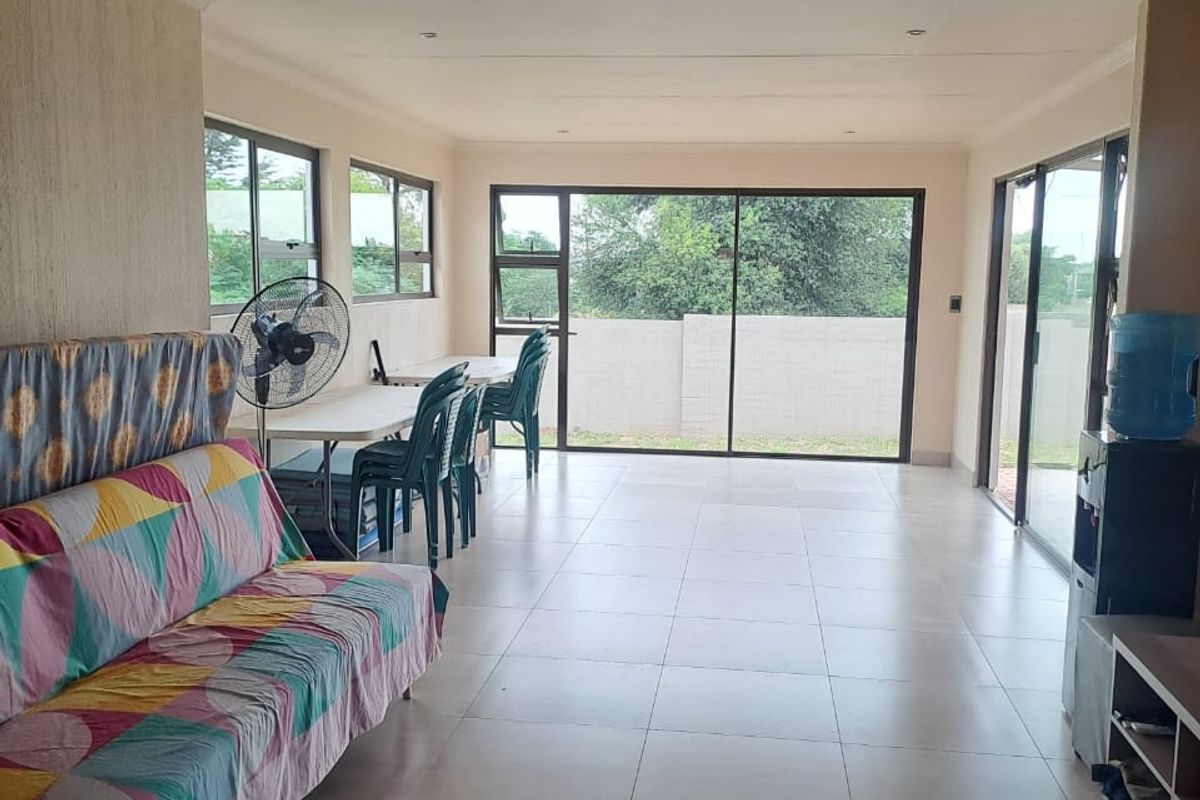 Spacious living area featuring large sliding glass doors, neutral tiled flooring, and recessed lighting, offering a bright and open layout.