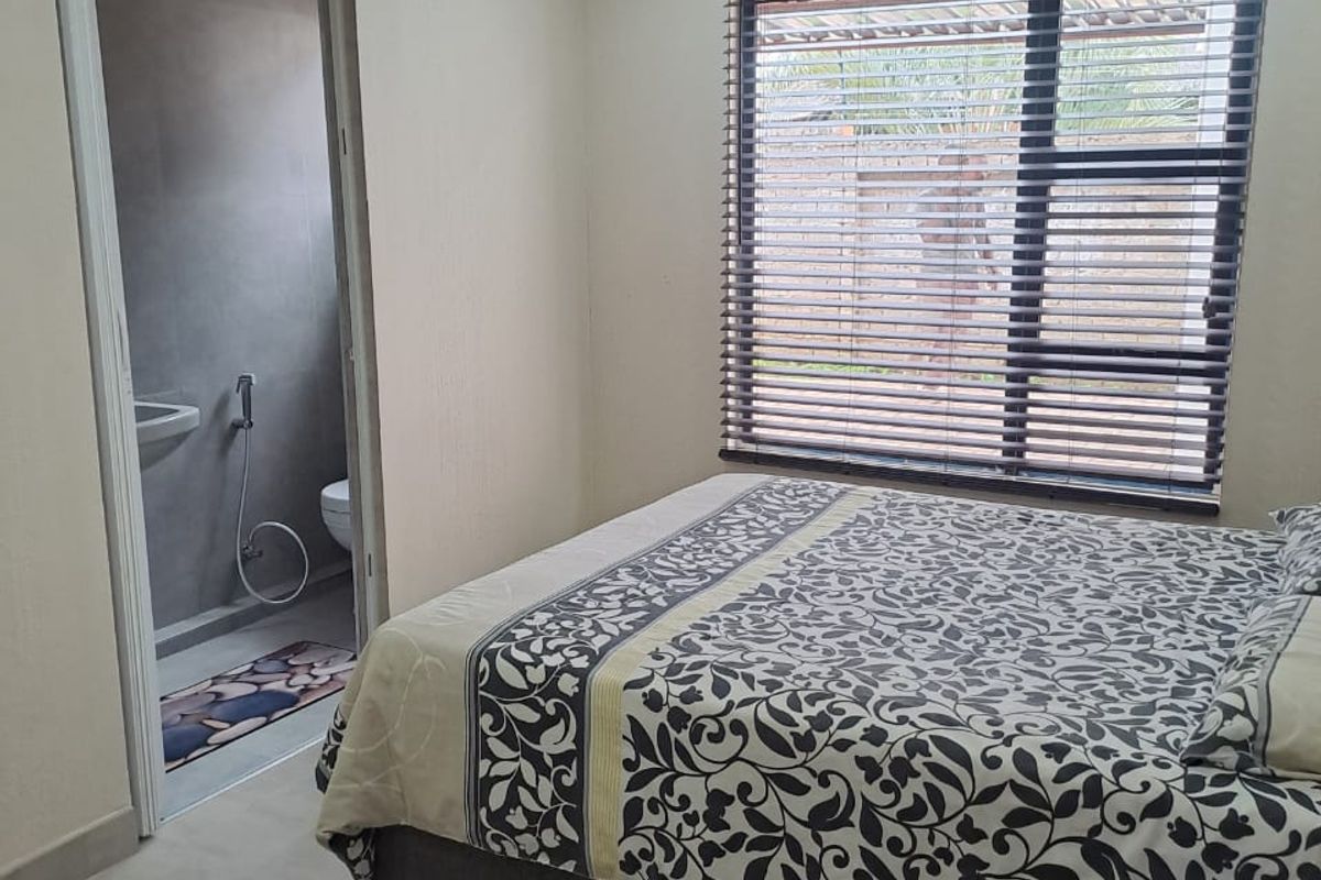 A well-maintained bedroom featuring tiled flooring, recessed downlighting, and venetian blinds, with direct access to an en-suite bathroom.