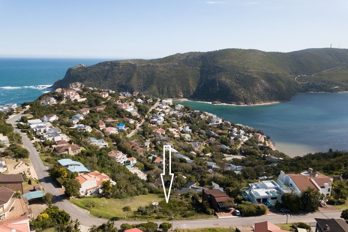 Aerial view of a vacant residential plot situated in a scenic coastal neighborhood with ocean and mountain views.