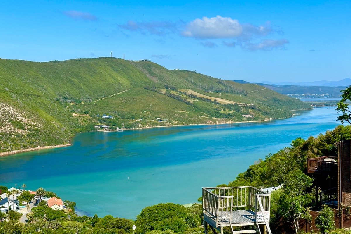 A scenic elevated view overlooking the lagoon and surrounding hills, featuring a wooden viewing platform in the foreground.