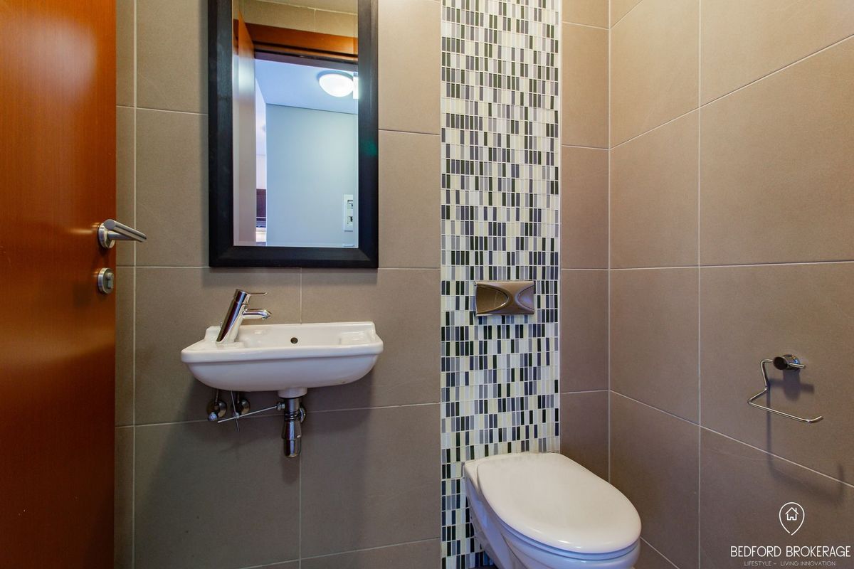 A modern guest bathroom featuring a wall-mounted basin, wall-hung toilet, and a decorative mosaic tile feature wall.