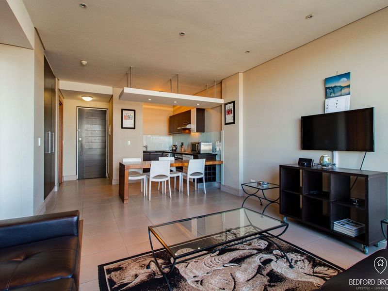 Open-plan living and kitchen area featuring tiled flooring, recessed lighting, and modern built-in cabinetry, creating a functional and cohesive living space.