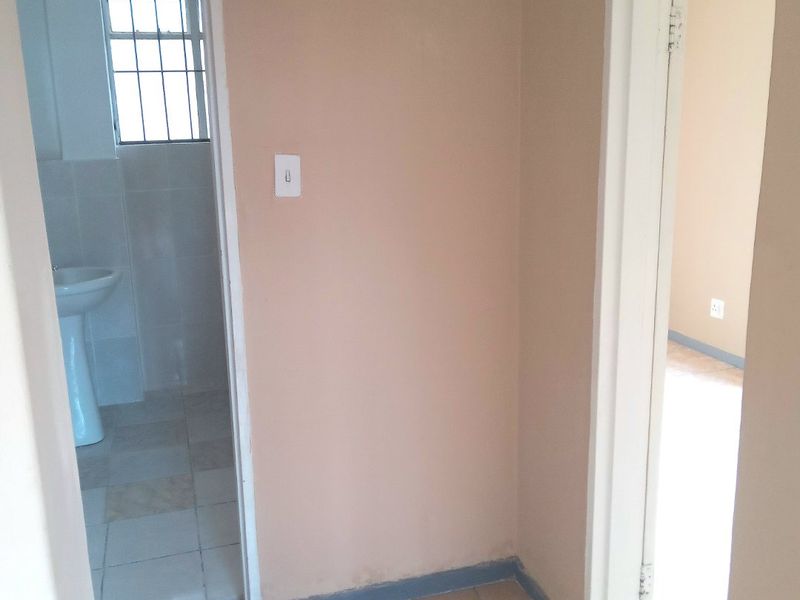 A functional hallway area connecting to a bathroom, featuring tiled flooring and neutral wall finishes.