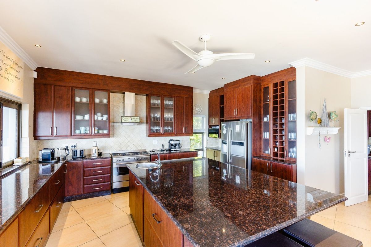 Spacious kitchen featuring dark wood cabinetry, granite countertops, a large central island, and stainless steel appliances, offering a functional and classic culinary space.