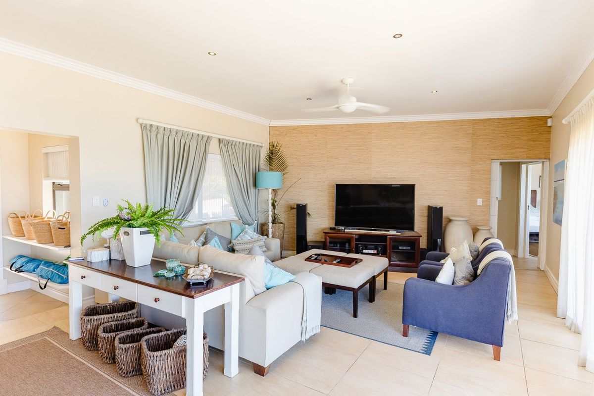 Spacious living room featuring tiled flooring, recessed downlights, a ceiling fan, and a textured feature wall.