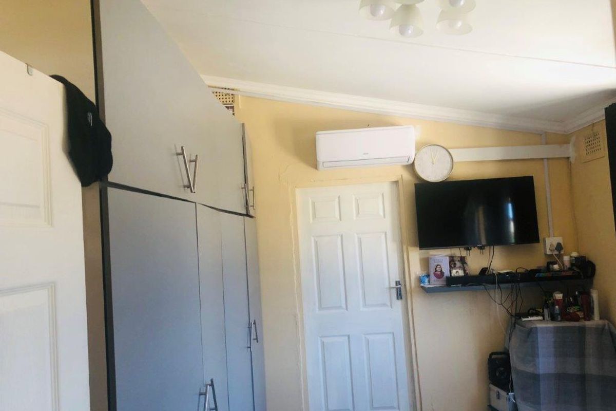 Bedroom featuring built-in cupboards, a wall-mounted air conditioning unit, and standard panel door access.