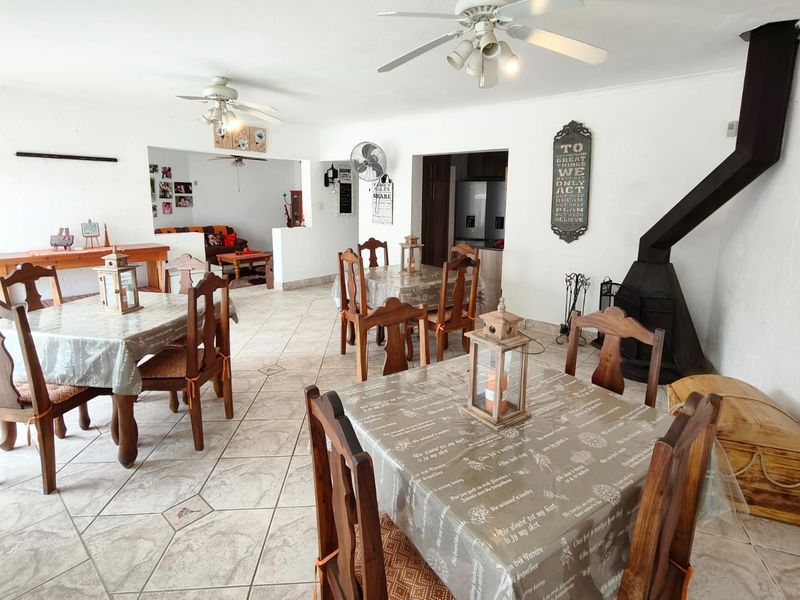 Spacious open-plan living and dining area featuring tiled flooring, ceiling fans, and a prominent freestanding fireplace.
