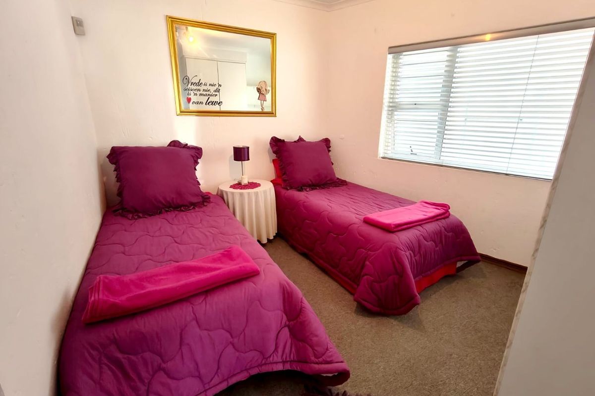 A functional bedroom featuring neutral walls, carpeted flooring, and venetian blinds, providing a simple and practical living space.
