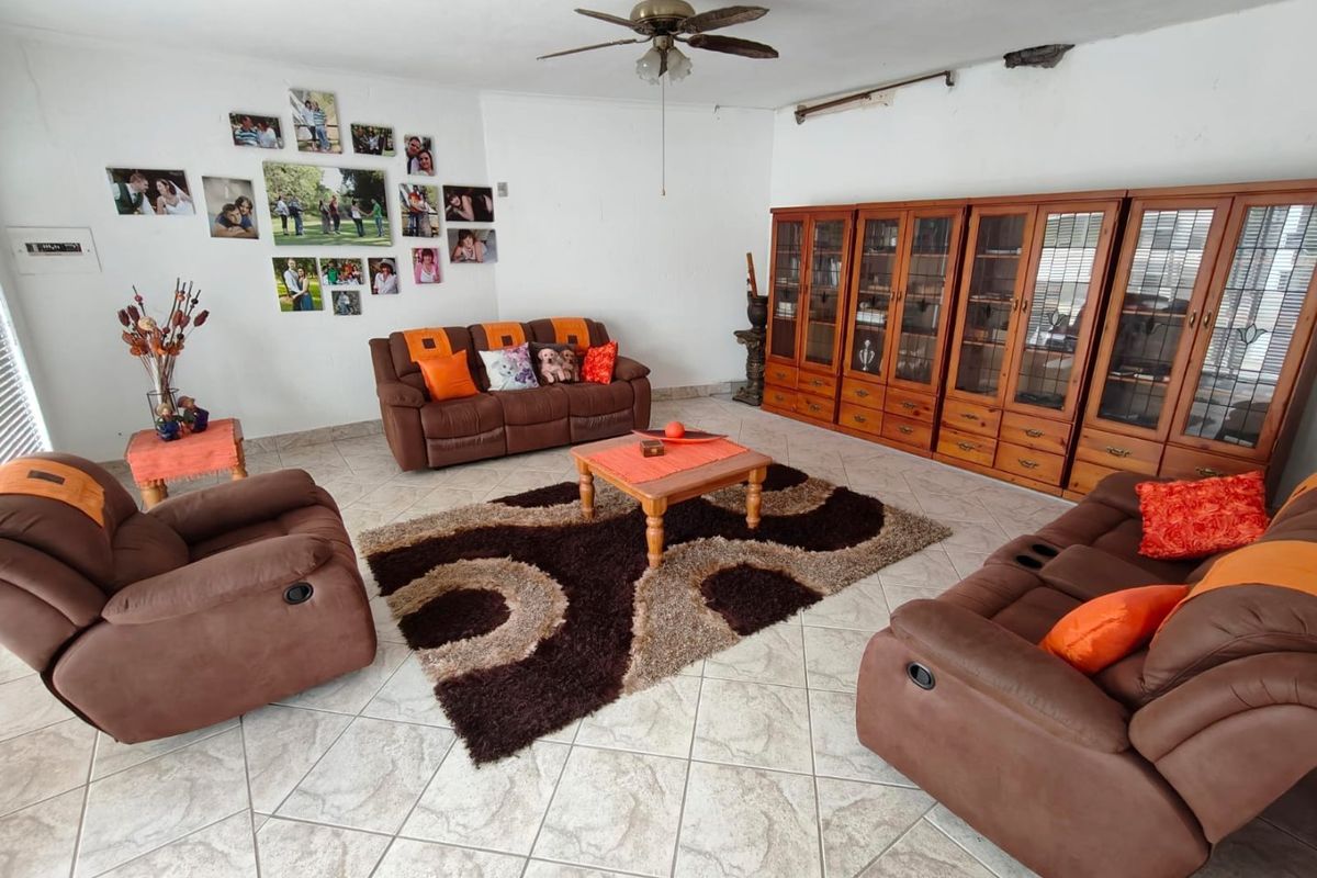 Spacious living room featuring ceramic floor tiles, a ceiling fan, and extensive built-in wooden cabinetry for storage.