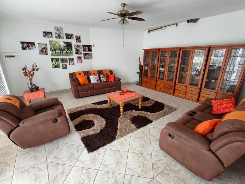 Spacious living room featuring ceramic floor tiles, a ceiling fan, and extensive built-in wooden cabinetry for storage.
