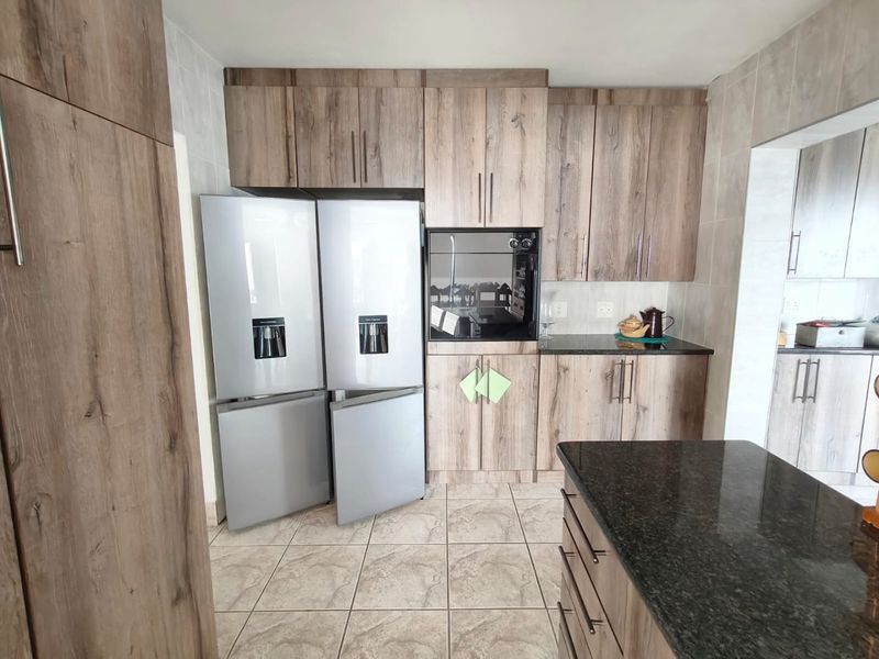A functional kitchen featuring wood-look cabinetry, granite countertops, tiled flooring, and a built-in oven with ample storage space.