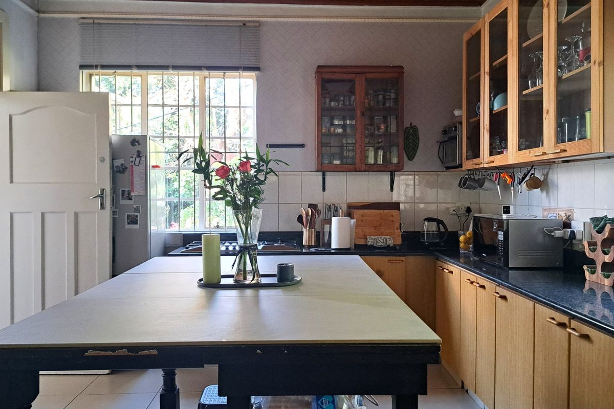 A functional kitchen featuring wooden cabinetry, tiled backsplash, and a central island, offering a practical layout with natural light from the window.