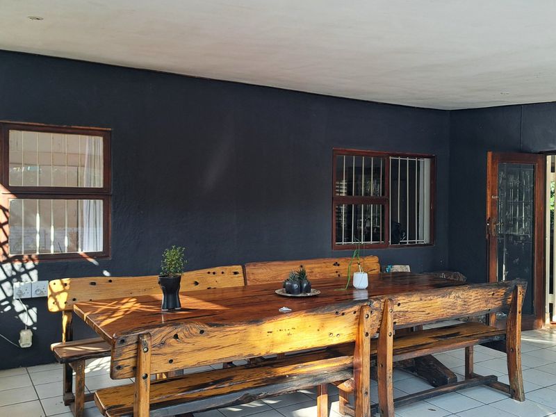 A covered patio area featuring tiled flooring, security bars on windows, and a security gate, providing a functional outdoor entertainment space.