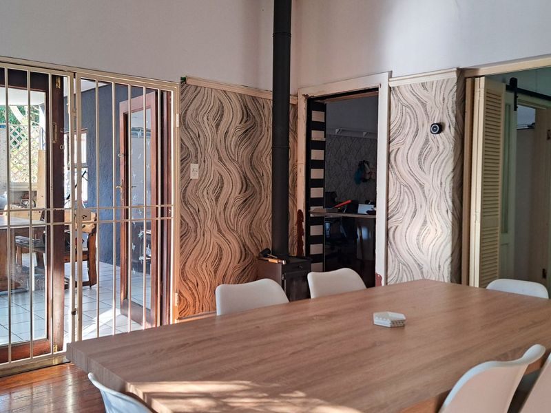 Dining area featuring timber flooring, a freestanding fireplace, and access to an outdoor patio through a security gate.