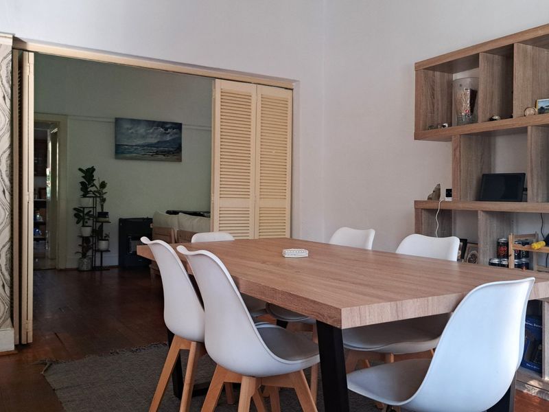 Dining room featuring timber flooring, a built-in shelving unit, and bi-fold doors leading to an adjacent living space.