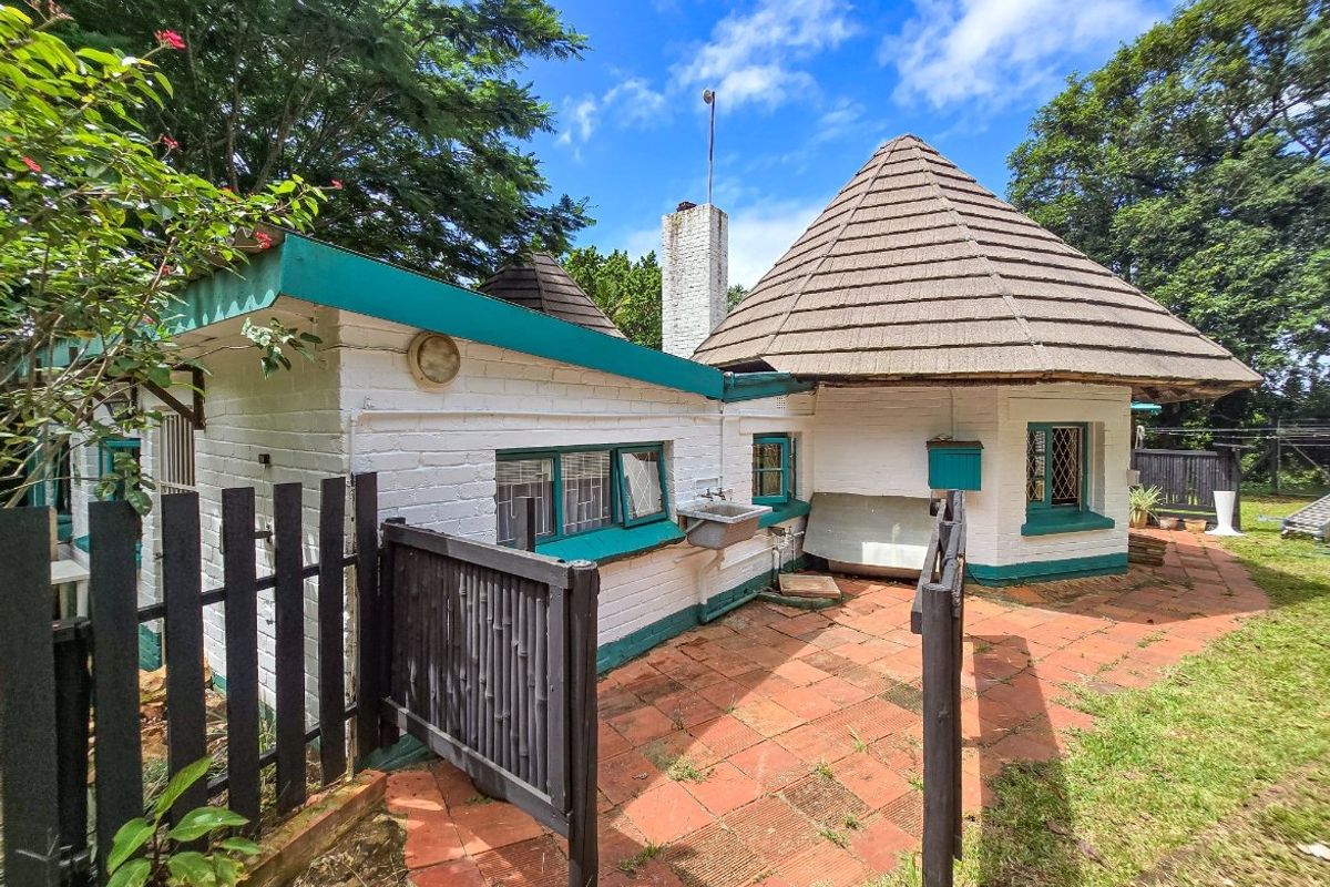 Rear exterior view of the property featuring a unique conical roof design, terracotta patio area, and an external utility sink.