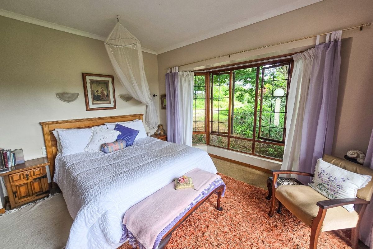 A cozy bedroom featuring a large bay window that provides natural light and views of the garden.
