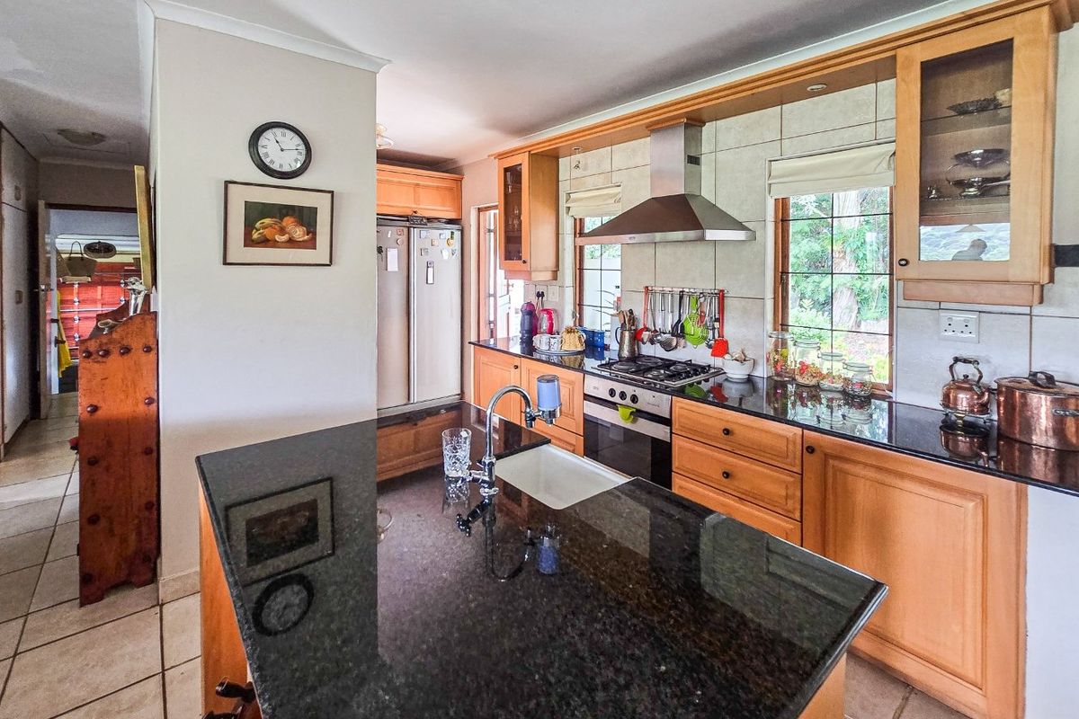 A functional kitchen featuring wooden cabinetry, granite countertops, a central island with a sink, and built-in cooking appliances.
