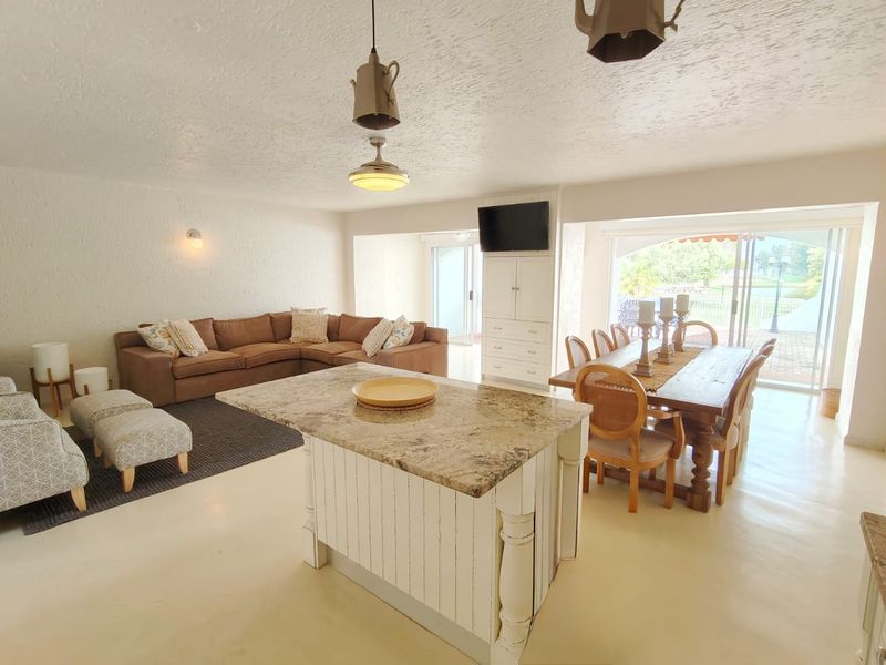 Spacious open-plan living and dining area featuring a central kitchen island with granite countertops and large sliding glass doors leading to the outdoors.
